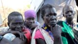 FILE - In this Dec. 16 2020 photo, Kallayn Keneng , foreground right, sits on the ground with three women, who all have lost chidren due to starvation when they were displaced from their villages due to fighting, in Lekuangole, South Sudan.