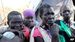 FILE - In this Dec. 16 2020 photo, Kallayn Keneng , foreground right, sits on the ground with three women, who all have lost chidren due to starvation when they were displaced from their villages due to fighting, in Lekuangole, South Sudan.