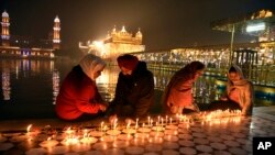 Sejumlah umat Sikh menyalakan lilin di Kuil Emas di Amritsar, India, 30 November 2020. 