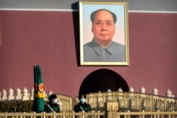 Policías paramilitares chinos montan guardia cerca de un retrato del líder Mao Zedong, en la Puerta de Tiananmen, en Beijing, el sábado 9 de enero de 2021. China dará las vacunas anticovid gratis a su población anunciaron autoridades de salud.