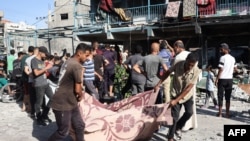 People use a blanket to transport a victim after an Israeli airstrike hit a school in Nuseirat, in the central Gaza Strip, Sept, 11, 2024