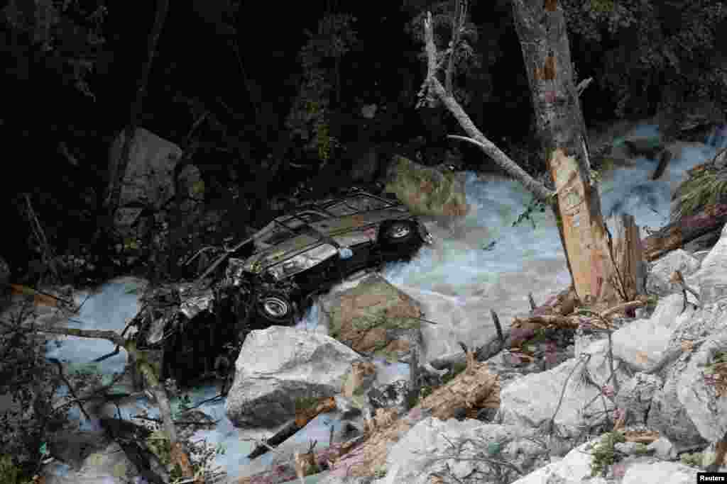 A car lies in a mountain creek beside a road that hit by a rockslide after an earthquake outside Jiuzhaigou, Sichuan province, China.