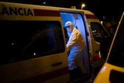 An emergency worker wearing a protective suit closes the door of an ambulance transferring a COVID-19 patient in Barcelona, Spain, March 27, 2020.