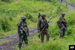 FILE - M23 rebels stand with their weapons in Kibumba, in the east of Democratic Republic of Congo, on Dec. 23, 2022.