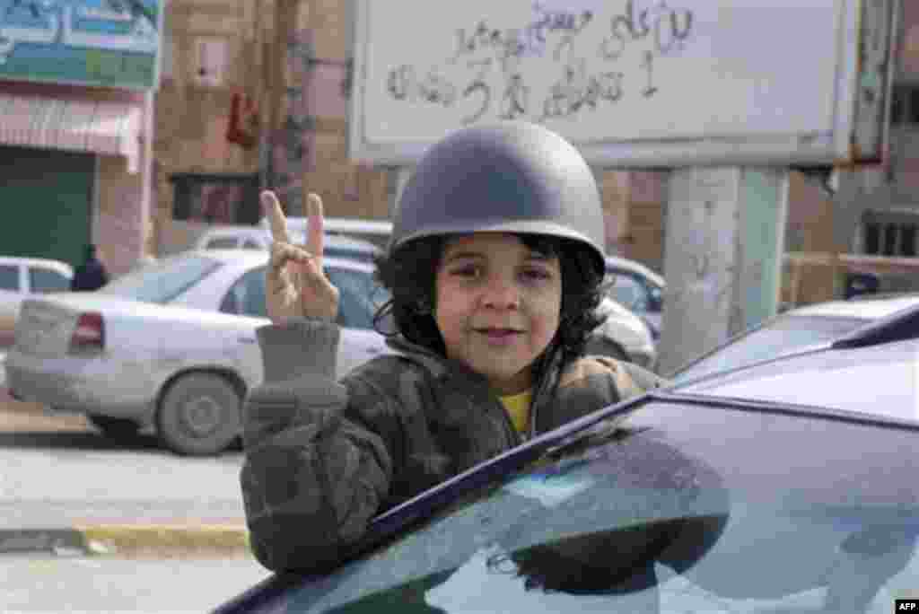 A girl sitting out of a vehicle window celebrates and displays the victory sign in Benghazi, Libya on Monday, Feb. 21, 2011. Libyan protesters celebrated in the streets of Benghazi on Monday, claiming control of the country's second largest city after blo