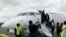 FILE - Passengers disembark from a Uganda Airlines Bombardier CRJ-900 plane during its relaunching flight to Jomo Kenyatta International Airport in Nairobi, Aug. 27, 2019.