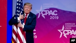 President Donald Trump hugs the American flag as he arrives to speak at Conservative Political Action Conference, CPAC 2019, in Oxon Hill, Md., Saturday, March 2, 2019.