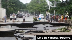 Des personnes se tiennent près de routes endommagées par des inondations après de fortes pluies à Dili, Timor oriental, le 5 avril 2021. 