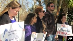 File - On Feb. 5, 2013, people hold signs protesting the use of of air guns in exploring for oil and natural gas in the North Atlantic Ocean during a news conference in Charleston, South Carolina.