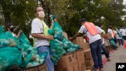 22일 미국 텍사스주 댈러스에서 마스크를 쓴 봉사자들이 저소득층에 지원할 식료품을 준비하고 있다.