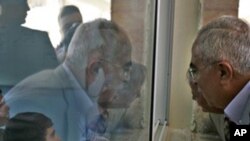 Palestinian Prime Minister Salam Fayyad, right, looks through a window into a classroom as he visits a school in the West Bank village of Dahiat Al-Barid on the outskirts of Jerusalem, Tuesday, Nov. 2, 2010.