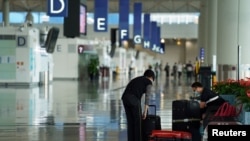 FILE - A woman, wearing a face mask following the coronavirus disease (COVID-19) outbreak, sorts luggage at Hong Kong International Airport in Hong Kong, Oct. 20, 2020. 