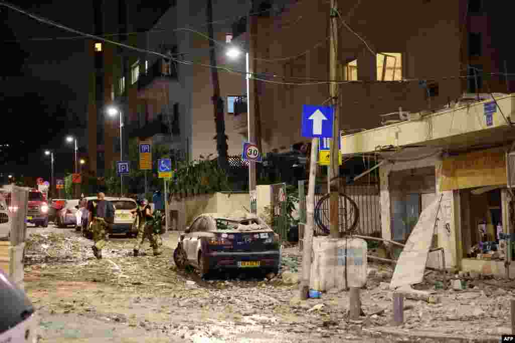 Members of the Israeli security forces walk along a debris-strewn street in Tel Aviv, after it was hit by a rocket fired by Palestinian militants from the Gaza Strip, Oct. 7, 2023.