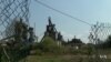 The now defunct Hayange steel plant is seen through a ripped chain-linked fence.