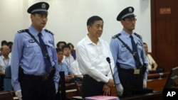 FILE - Bo Xilai, center, in court on charges of bribery, embezzlement and abuse of power in a case set in motion by his wife's murder of a British businessman.