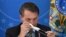 Brazil's President Jair Bolsonaro puts on a mask during a news conference on the new coronavirus at the Planalto Presidential Palace in Brasilia, Brazil, March 18, 2019. 