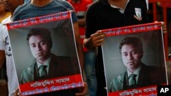 FILE - People carry portraits of student activist Nazimuddin Samad as they attend a rally to demand arrest of three motorcycle-riding assailants who hacked and shot Samad to death, in Dhaka, Bangladesh, April 8, 2016.