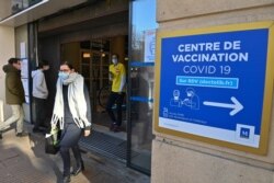 FILE - People pass by a sign reading "COVID-19 vaccination center," in Montpellier, France, Jan. 19, 2021.