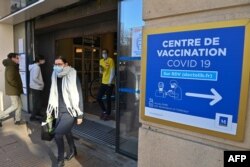 FILE - People pass by a sign reading "COVID-19 vaccination center," in Montpellier, France, Jan. 19, 2021.