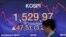 A currency trader walks by a screen showing the Korea Composite Stock Price Index (KOSPI) at the foreign exchange dealing room in Seoul, South Korea, March 24, 2020. 