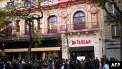 FILE - People stand in front of the Bataclan concert venue during ceremonies across Paris marking the second anniversary of the terror attacks of November 2015 in which 130 people were killed, in the French capital, 11.13.2017