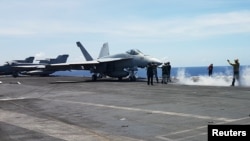 An F18 fighter prepares to take off at the flight deck of the USS Theodore Roosevelt while transiting the South China Sea, April 10, 2018. 