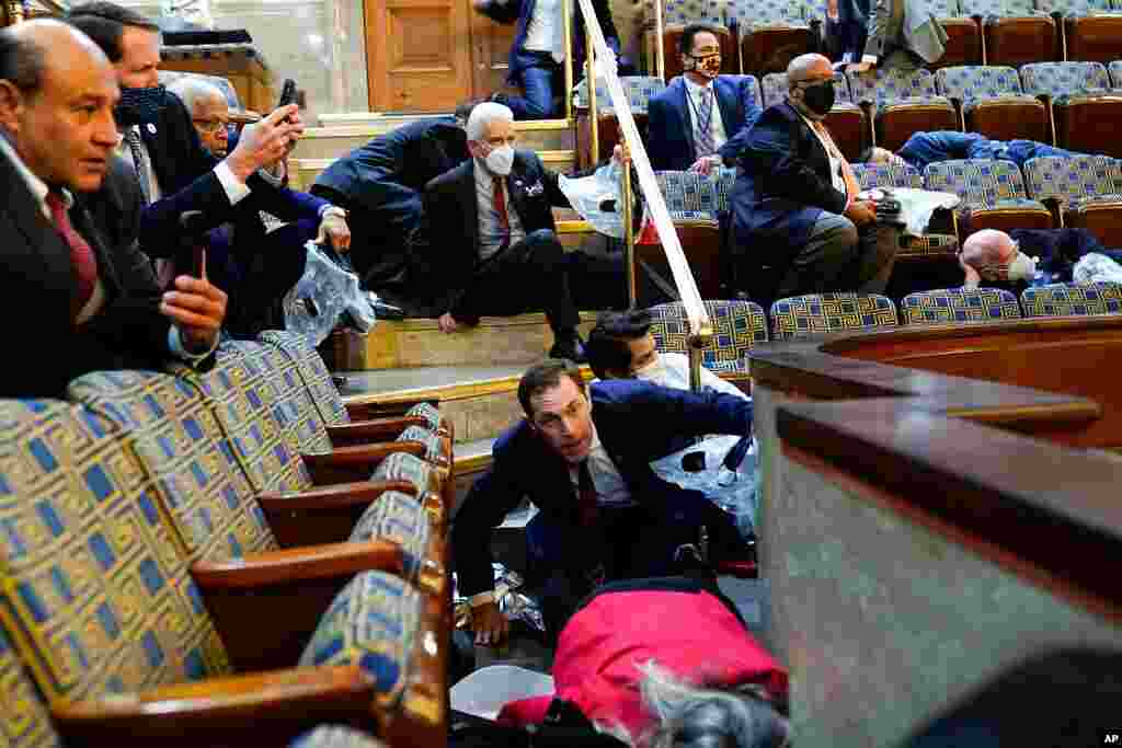 People shelter in the House gallery as protesters try to break into the House Chamber at the U.S. Capitol, Jan. 6, 2021, in Washington. 