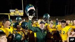 Paradise High School head football coach Rick Prinz, center, celebrates with his team after defeating Live Oak High School, 56-0, in their Northern California Division III playoff game in Paradise, Calif., Nov. 15, 2019. 