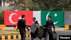 FILE - Police walk near the national flags of Pakistan and Turkey displayed along a road in Islamabad, Pakistan, Nov. 16, 2016. 