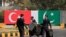 FILE - Police walk near the national flags of Pakistan and Turkey displayed along a road in Islamabad, Pakistan, Nov. 16, 2016. 