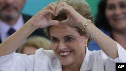 Presiden Brazil Dilma Rousseff membuat tanda hati (cinta) dengan tangannya pada pertemuan dengan guru dan pelajar di Brasilia, Brazil (12/4).