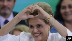 Brazil's President Dilma Rousseff makes a heart sign during a ceremony with teachers and students at Planalto presidential palace in Brasilia, Brazil, Tuesday, April 12, 2016. 