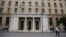 People walk past the Bank of Greece headquarters, in central Athens, March 27, 2015. 