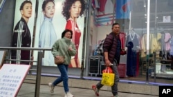 Shoppers walk by an apparel store in Shanghai on March 18, 2024.