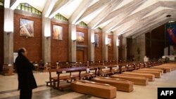 Pastor Paroki Seriate, Don Mario, berdiri dekat jajaran peti jenazah di Gereja San Giuseppe di Seriate, dekat Bergamo, Lombardy, 26 Maret 2020. (Foto: AFP)