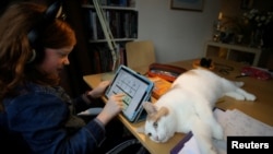 Alice Wilkinson is joined by her cat Freddie as she does her maths online schooling amid the outbreak of COVID-19 in Manchester, Britain, January 15, 2021. REUTERS