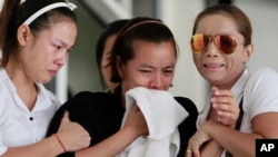 Noppawan Chairat, center, the mother of two children killed in Sunday's bomb attack on an anti-government protest site, Noppawan Chairat, is held by her family members as they wait for their bodies at a hospital in Bangkok, Thailand, Monday, Feb. 24, 2014