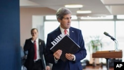 U.S. Secretary of State John Kerry picks up his notebook after answering questions from members of the media before his departure from Ben Gurion International Airport in Tel Aviv on Friday, Dec. 6, 2013.