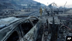 Fire crews search for hot spots among destroyed homes in the Rancho Monserate Country Club community Friday, Dec. 8, 2017, in Fallbrook, Calif. The wind-swept blazes have forced tens of thousands of evacuations and destroyed dozens of homes in Southern California. (AP Photo/Gregory Bull)