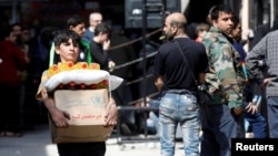 FILE - A boy holds a cardboard box of food aid received from the World Food Program in Aleppo's Kalasa district, Syria, April 10, 2019.