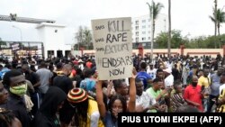 Seorang gadis membawa plakat bertuliskan "Pembunuhan Pasukan Khusus Ant-Robbery Squad (SARS), Pemerkosaan SARS, Pemerasan SARS, Akhiri SARS Sekarang" dalam perjalanan ke sebuah rumah pemerintah. (Foto: AFP//Pius Utomi Ekpei)