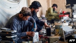 Sejumlah pelebur tampak berusaha mengambil emas dari kamera dan alat navigasi bekas di sebuah bengkel di distrik Spin Boldak, provinsi Kandahar, Afghanistan, pada 24 Agustus 2024. (Foto: AFP/Wakil Kohsar)