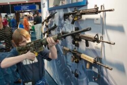 FILE - A young man, who chose not to give his name, sizes up an assault style rifle during the National Rifle Association's annual convention in Houston, Texas, May 3, 2013.