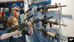 A young man sizes-up an assault style rifle during the National Rifle Association's annual convention in Houston, Texas, May 3, 2013. 