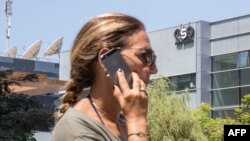 Una mujer habla por su celular mientras pasa frente al edificio que alberga al grupo israelí NSO, fabricante del software espía Pegasus, en Herzliya, cerca Tel Aviv, el 28 de agosto de 2016.