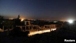 FILE - Vehicles drive past damaged buildings in al-Rai town, northern Aleppo countryside, Syria, Oct. 2, 2016. 