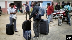 Para mahasiswa membawa barang-barang mereka saat meninggalkan kampus Universitas Kiriki di Bujumbura, Burundi, 30 April 2015. (AP Photo/Jerome Delay)