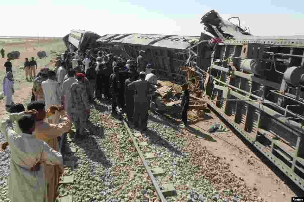 Para petugas penyelamat dan warga berkumpul di dekat kereta penumpang yang tergelincir akibat serangan bom di Dera Murad Jamali, provinsi Balochistan, Pakistan.