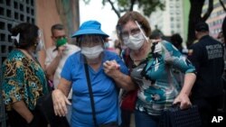 Dos mujeres ingresan al hotel Alba Caracas para recibir su primera dosis de la vacuna Sputnik V, luego de estar en fila por más de 5 horas, en Caracas, el 31 de mayo de 2021.