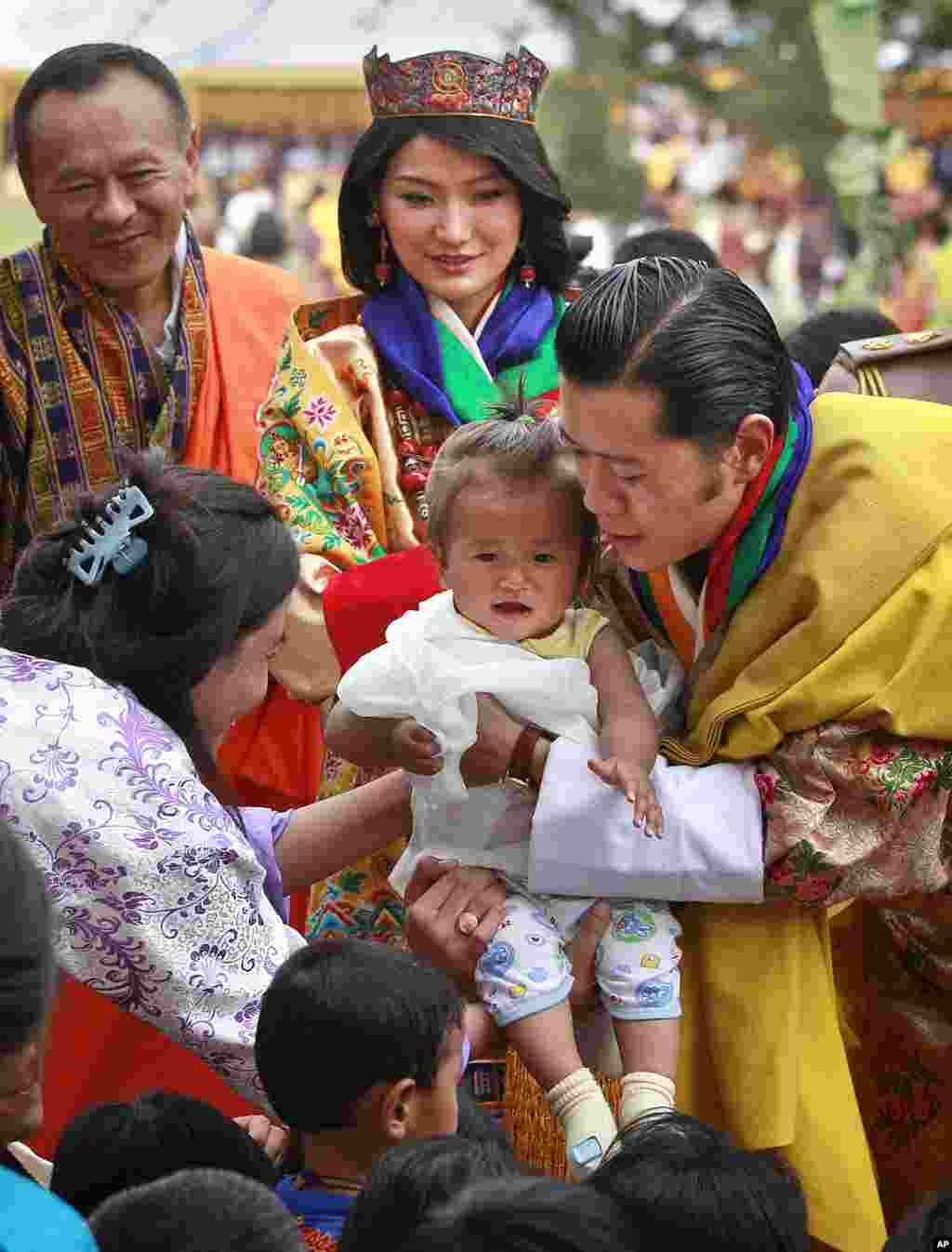 King Jigme Khesar Namgyel Wangchuck holds a young child as he greets locals with Queen Jetsun Pema, center rear, during a celebration after they were married at the Punakha Dzong in Punakha. (AP)